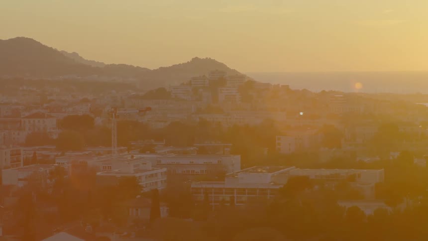 The sun sets behind a mountain side neighborhood