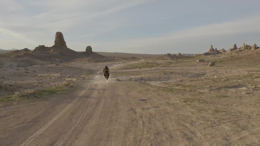 A person rides a dirt bike on a desert pathway