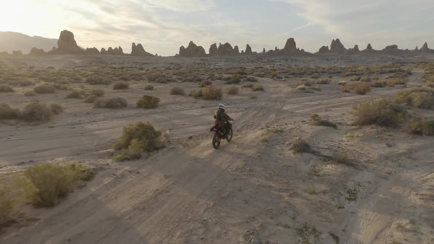 A person riding a motorbike along a dirt path in the desert