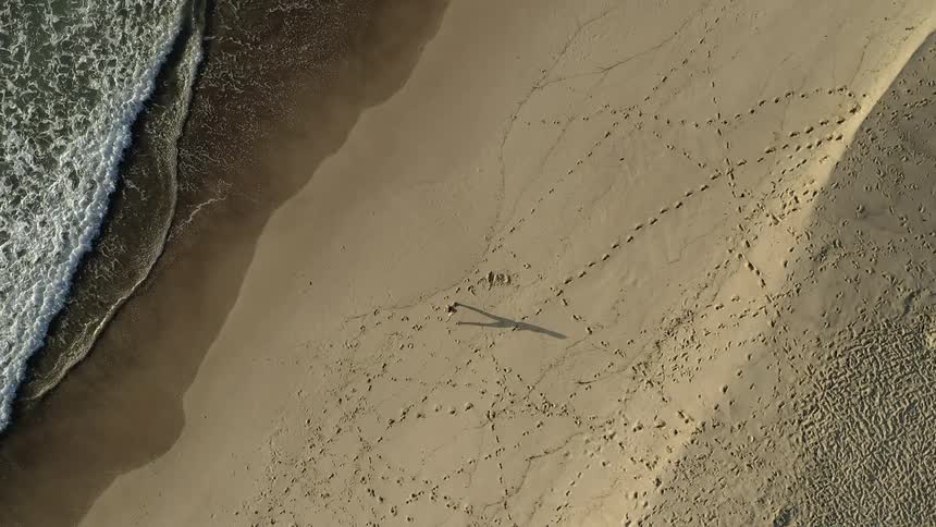 A person alone on a sandy beach with waves coming onshore