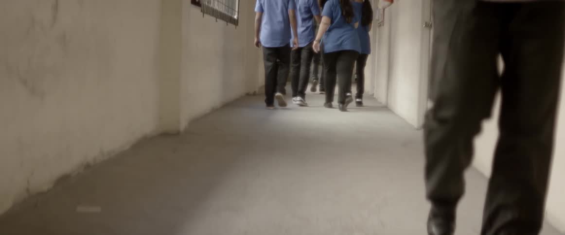 A group of people in blue shirts walking down a hallway