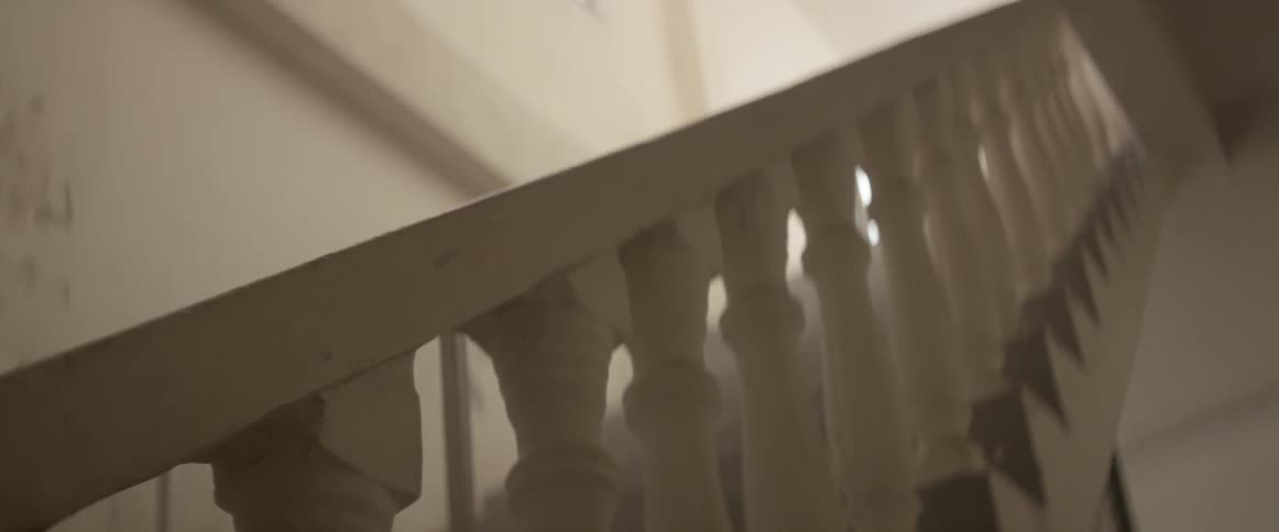 The white wooden handrail and balusters of an interior staircase