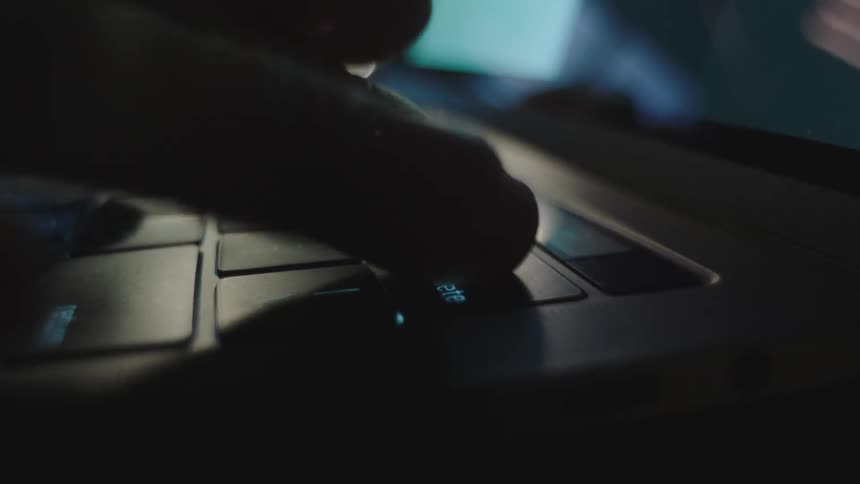 A person types on a laptop and pushes the delete key repeatedly