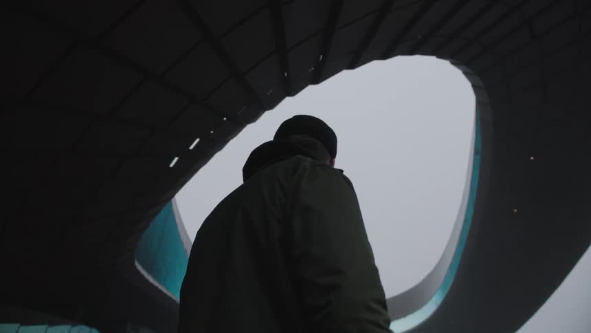A man stands under an architectural sculpture