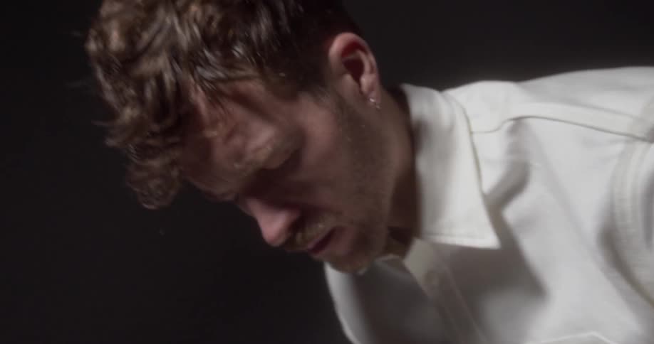 A man stands with his eyes tightly closed