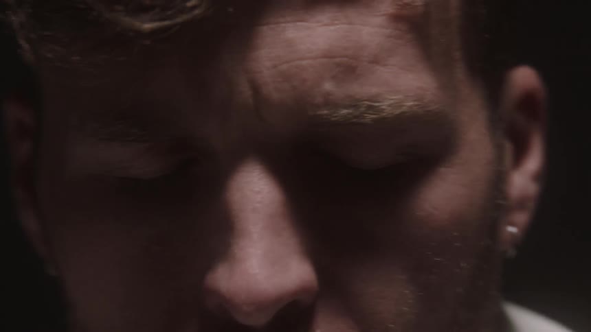 A light flashes behind a man with his eyes squeezed tightly shut