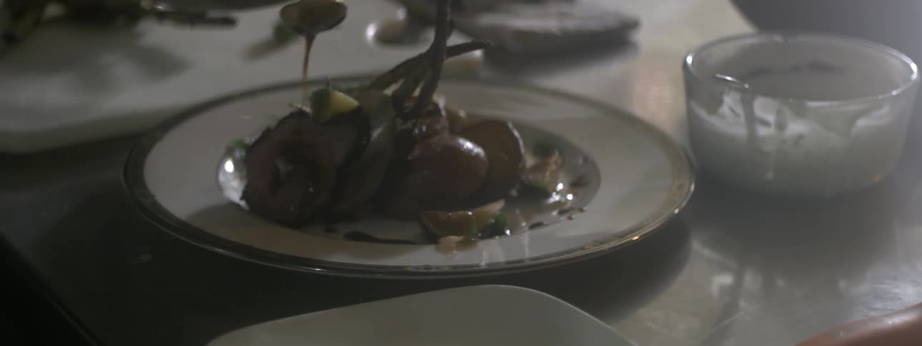 A person pours sauce over lamb chops