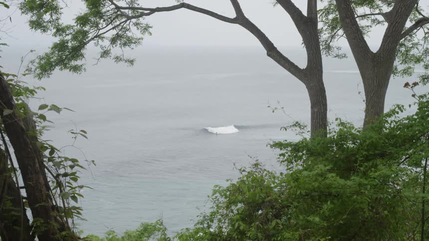 A distant pair of surfers riding a wave