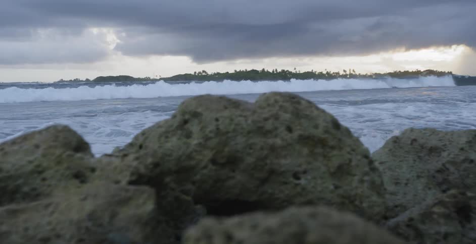 Ocean waves wash ashore a rocky beach on a cloudy day