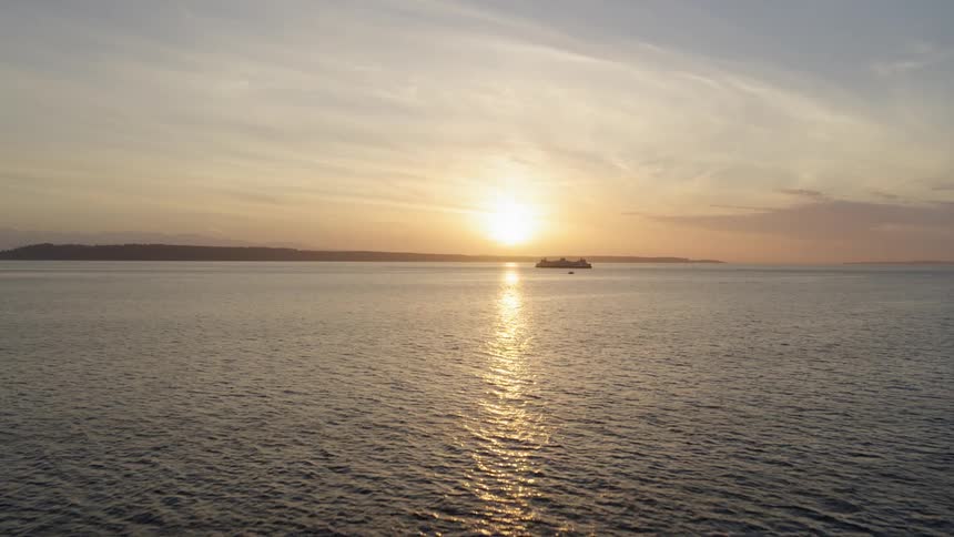 Vehicle ferry sailing along calm ocean water at sunset