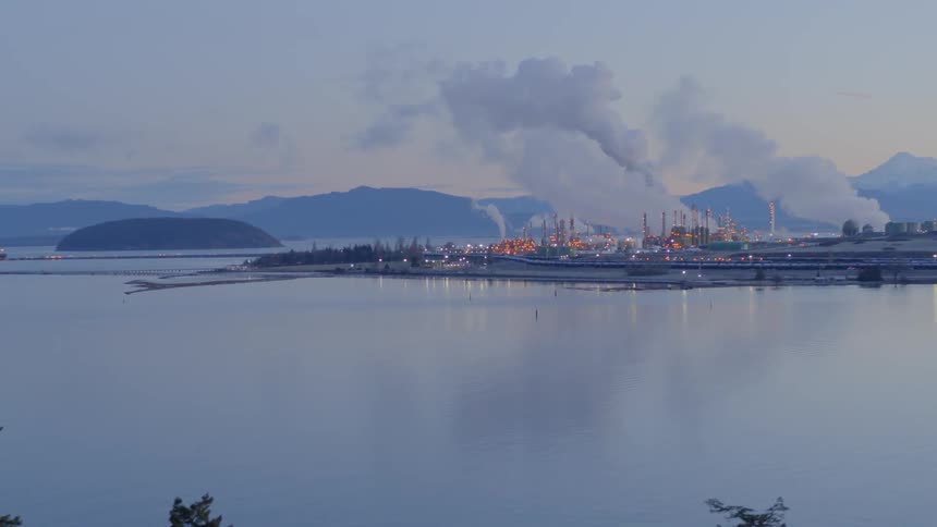 Aerial reveal of a large refinery complex and oil shipping terminal along the water