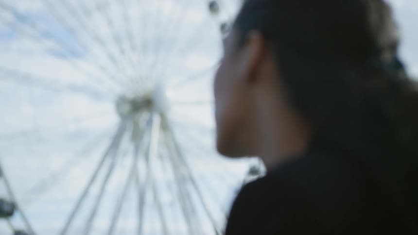 Woman looks up at ferris wheel