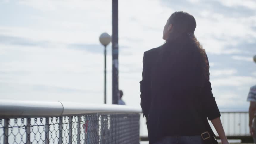 Woman walks along water side paved area