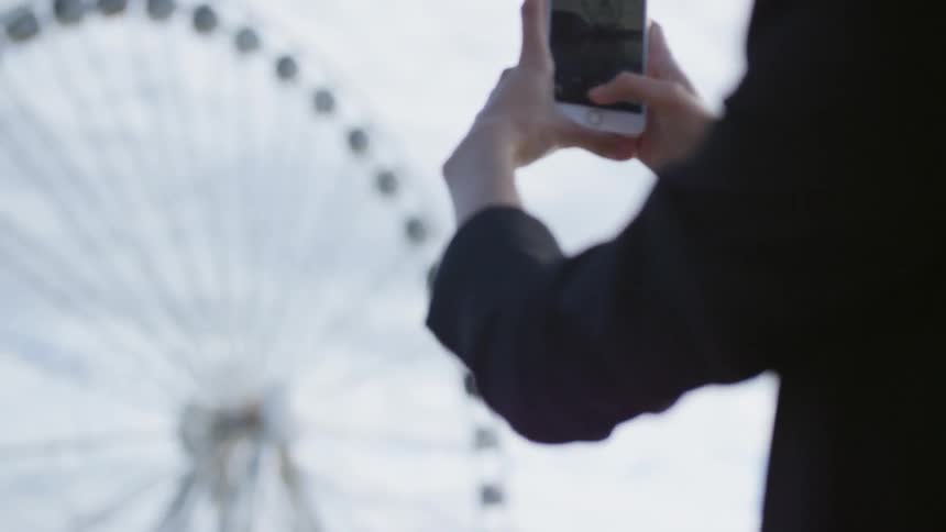 A woman taking a picture of a ferris wheel