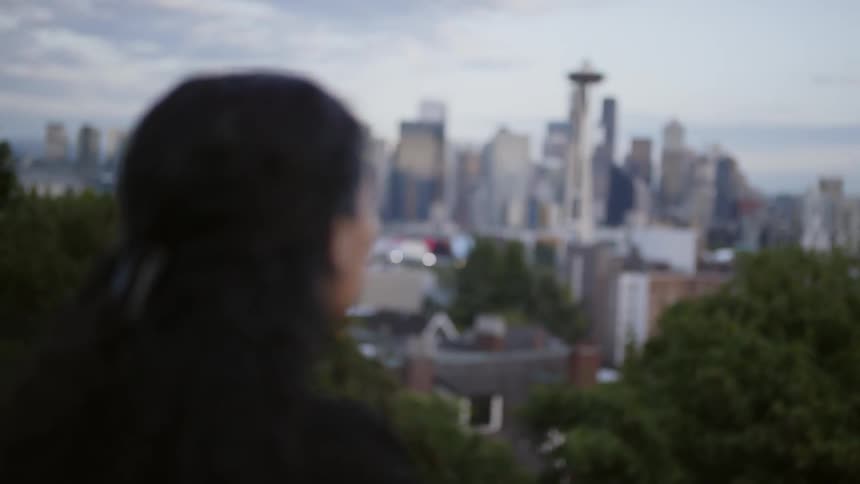 A woman stands on a hill overlooking the city