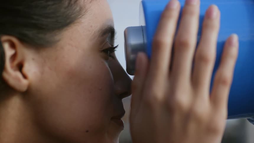 Woman looks through coin operated telescope