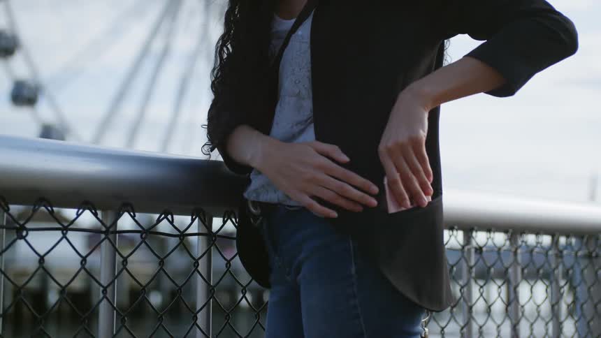 A woman waiting on the bridge near the ferris wheel
