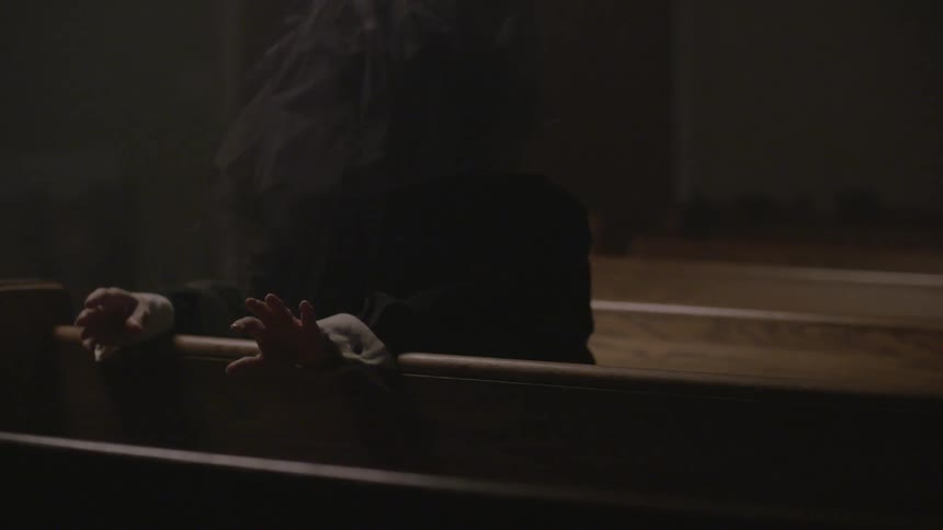 A person moves their hands on a church pew