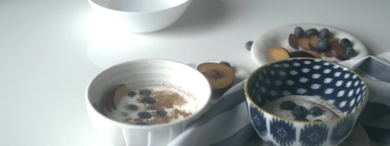 Two bowls of yogurt and a plate of fruit