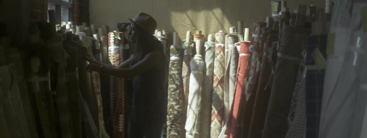 A woman in a light brown hat touches wrapped up fabric