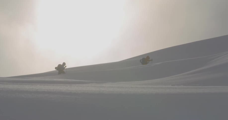 Two people hike through sloping terrain