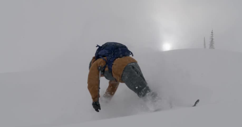 Skier twisting then falling while skiing down a slope