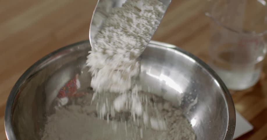 Flour being poured into an iron bowl