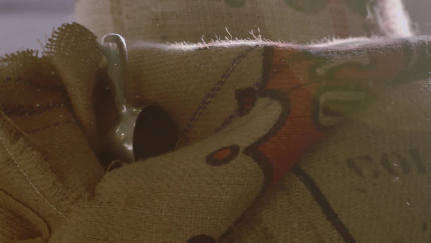 A burlap sack with a silver scoop in the sunlight