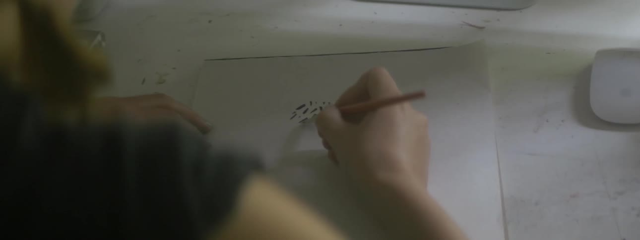 A woman paints dots and lines on a white sheet of paper
