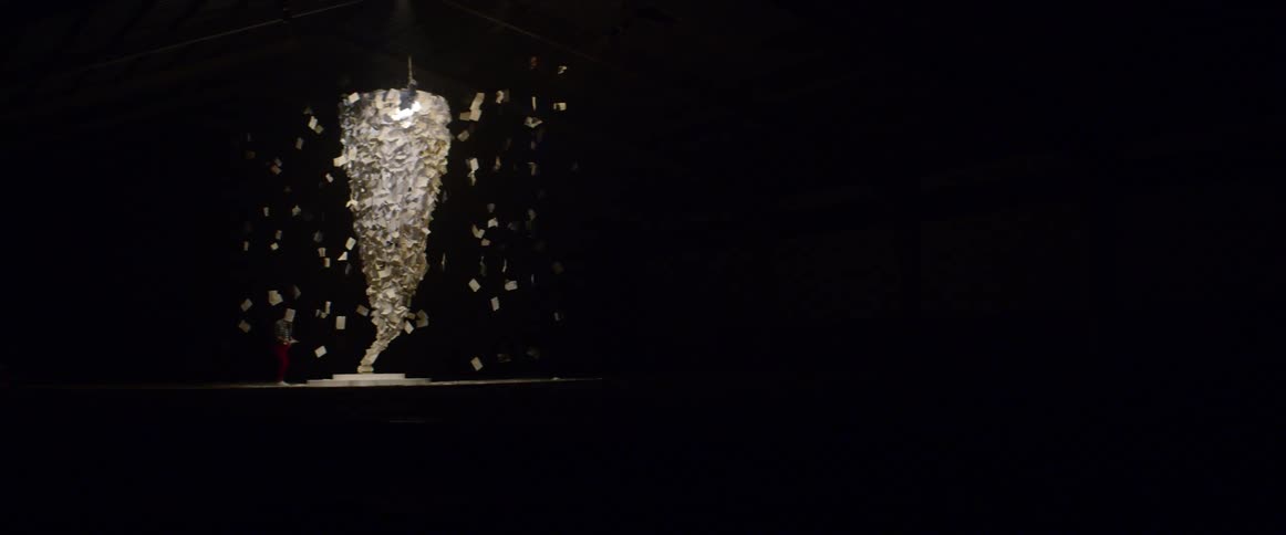 Postcards suspended on string around a light source as aperson reads
