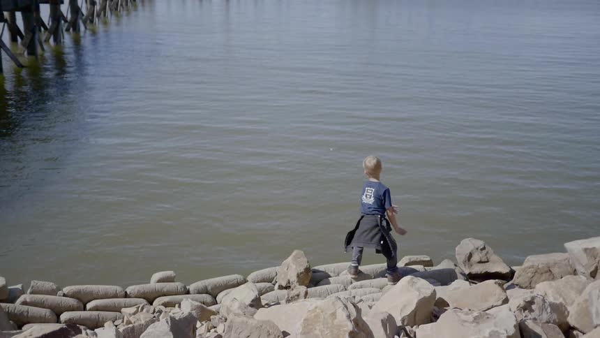 A child throwing a rock into the river