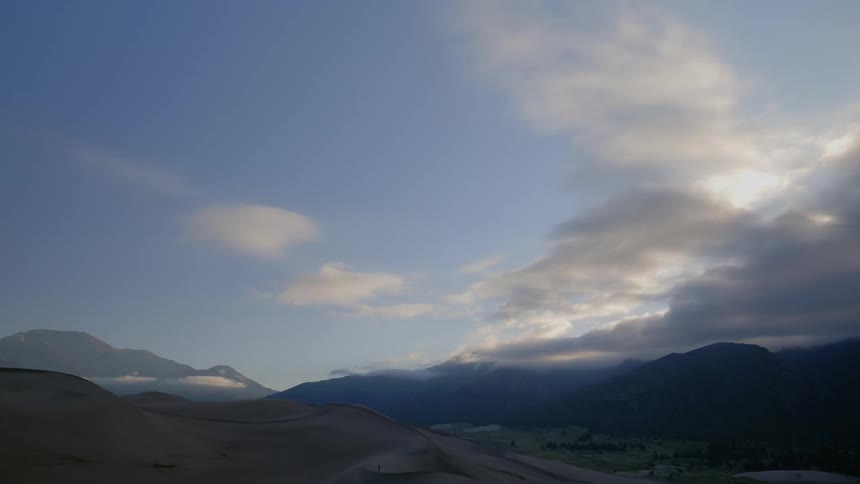 Clouds are moving in the horizon above the hills