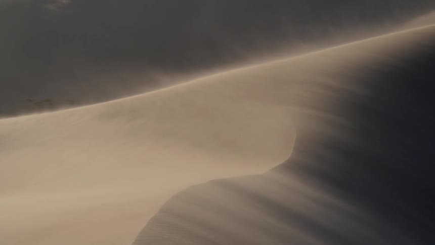 Sand lifts off of the surface of dunes