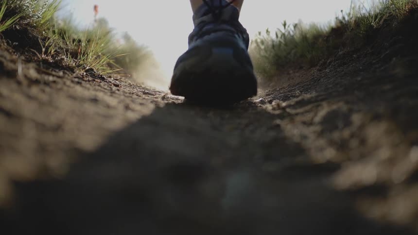 A person walking along a dirt path during the day