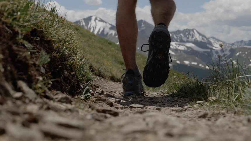 A man walks along a mountainside pathway
