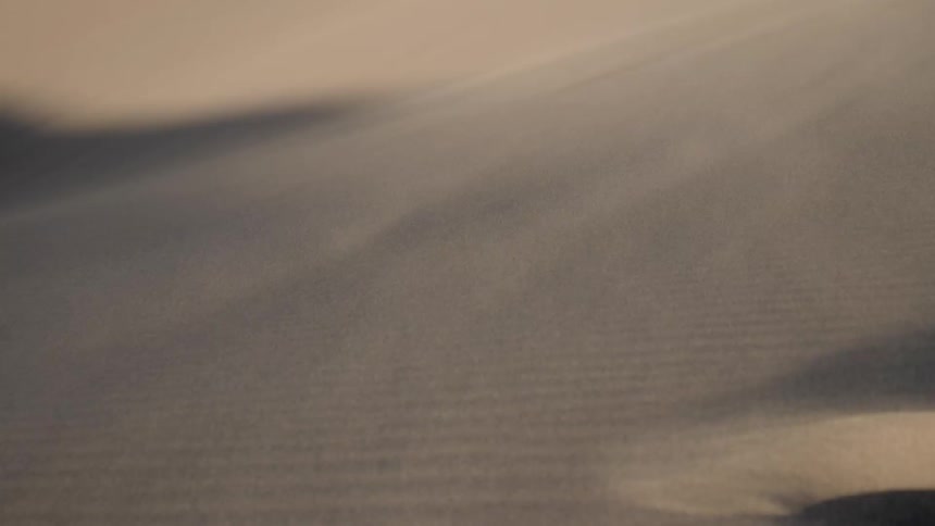 Wind blows sand across desert dunes
