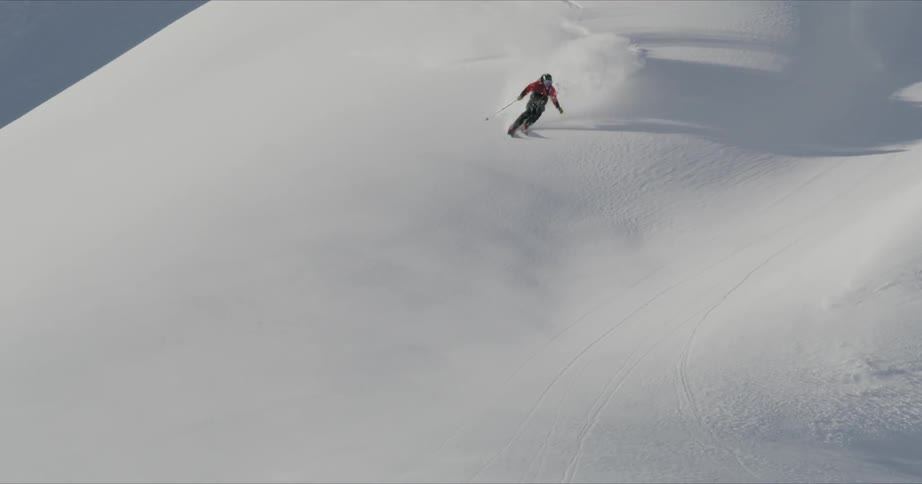 A person jumps down a snowy slope on skis