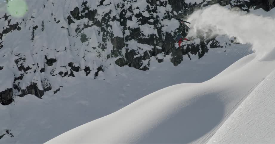 A skier jumping off a snow mound and doing a back flip before landing