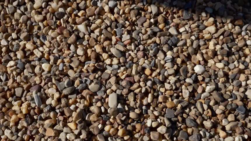Rocks of varying sizes and colors tumble as light passes overhead