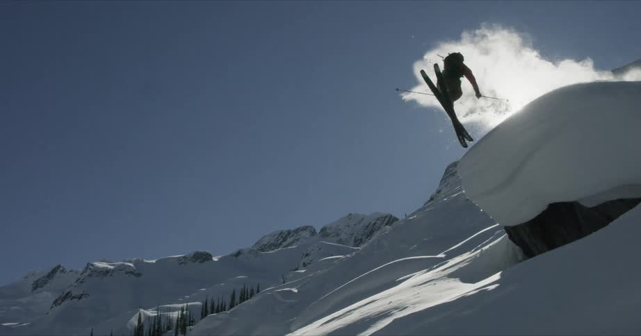 A person is skiing off the hill doing a spin