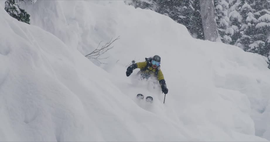 A man is skiing down a mountain while its snowing