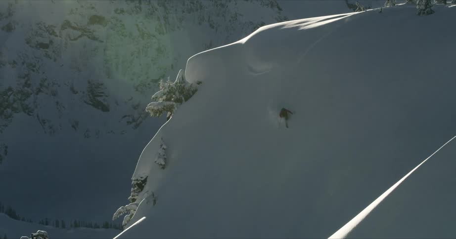 A person skis down a steep mountainside cliff