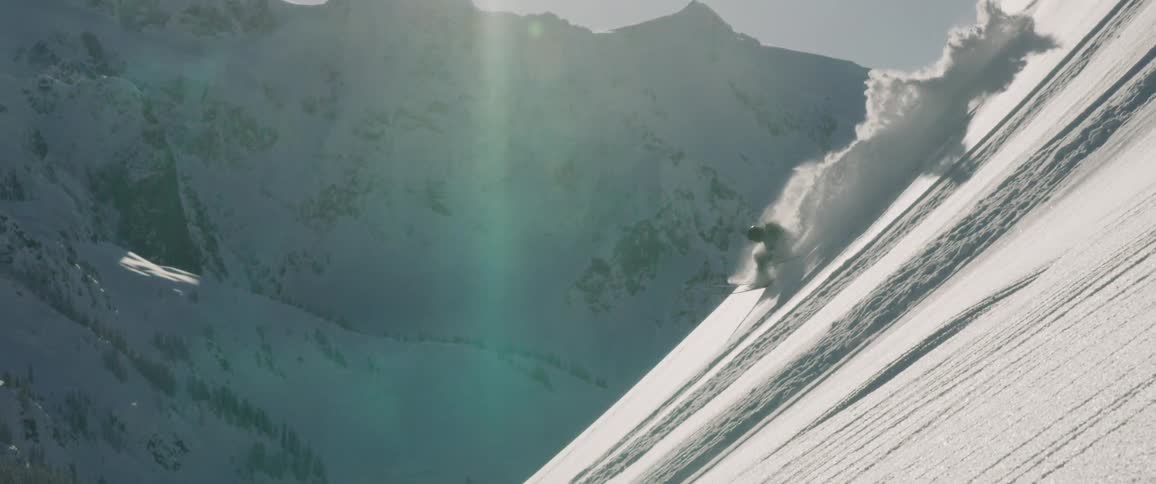 A man jumping from a snowy mountain apex with a snow board