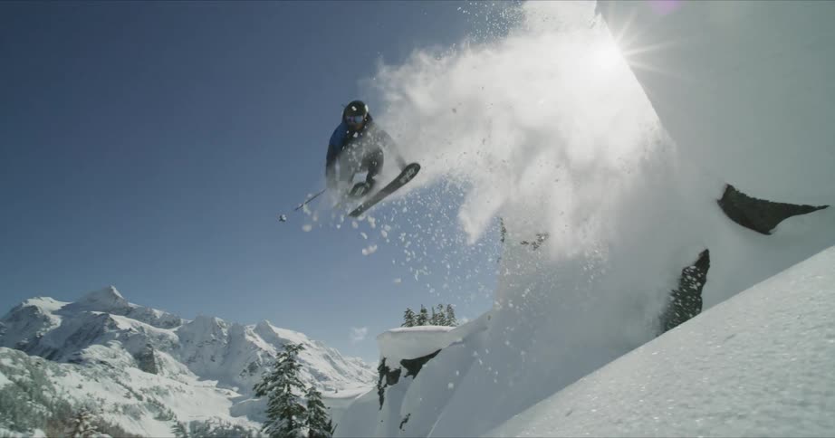 A man with blue jacket jumping with a snow board