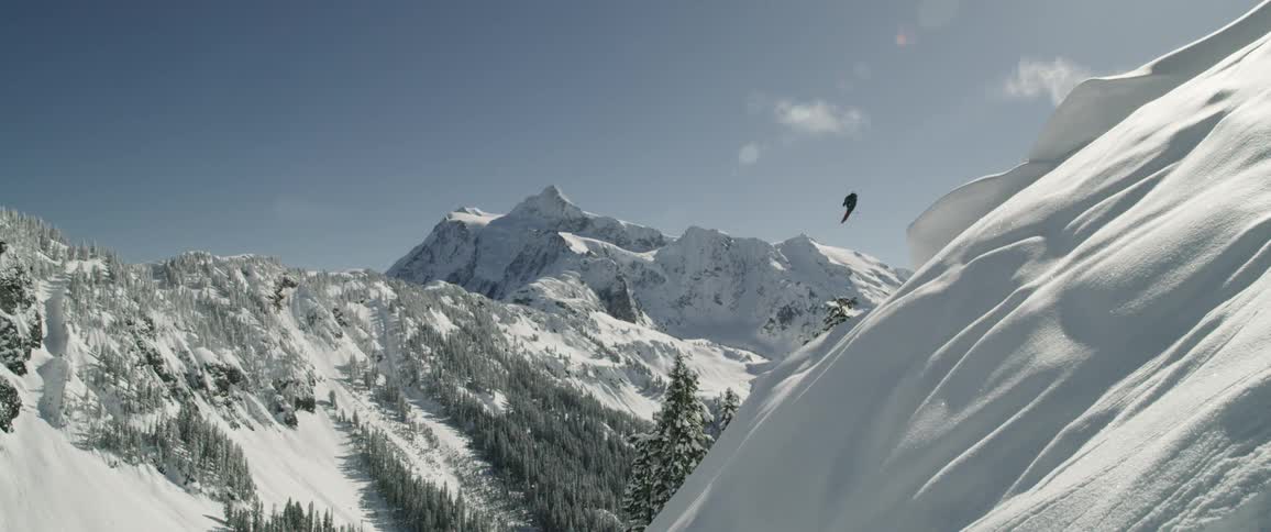 A person skis off the side of a snow covered mountain