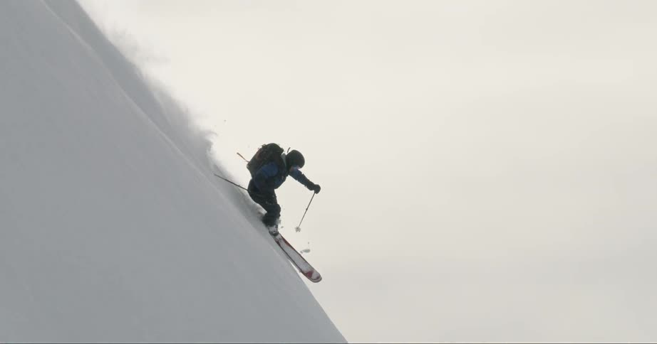 A person wearing a backpack is skiing down an extremely vertical slope of a mountain
