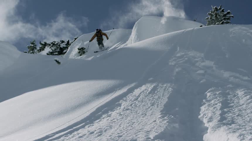 A skier jumps down a powdery hill