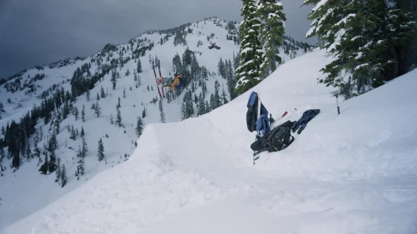 Skier is jumping off a ridge in a remote area on a winters day