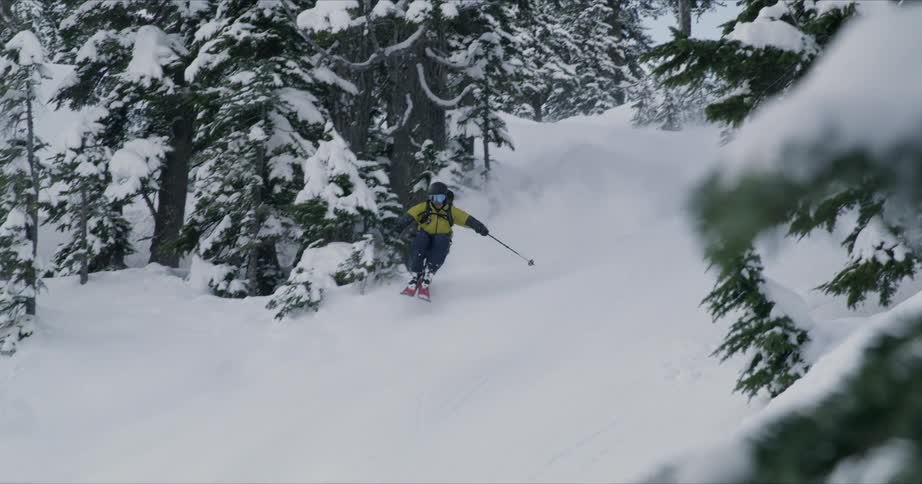 A skier falling over while attempting to ski down a set of snowy hills