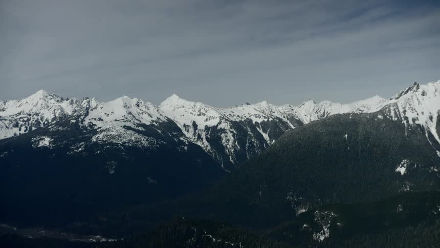 Aerial view of snow capped mountain range on a cloudy day